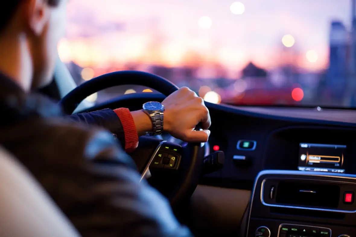 Hände am Lenkrad während einer Fahrstunde in der Abenddämmerung